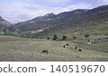 Various Horses Feed Peacefully Amidst Rolling Hills And Distant Village Under Sunny Mountain Skyline . Creative 140519670