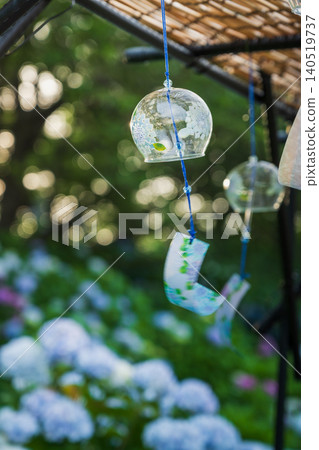 Wind chimes illuminated by the setting sun, with hydrangeas in Gongendo Park in the background. 140519737