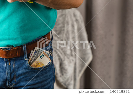 Details of a man's hand holding a smartphone with cash in his jeans pocket Details of a man's hand holding a smartphone with cash in his jeans pocket 140519851