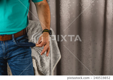 Man showing empty pocket while wearing jeans and shirt indoors Man showing empty pocket while wearing jeans and shirt indoors 140519852