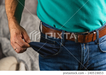 Man checks empty pocket for cash while wearing jeans and belt Man checks empty pocket for cash while wearing jeans and belt 140519853