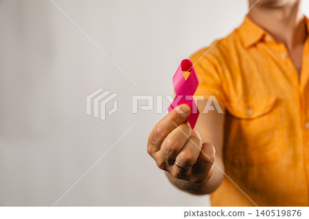 Man holds pink ribbon in support of health awareness campaign Man holds pink ribbon in support of health awareness campaign 140519876