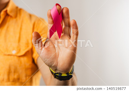 Man holding pink awareness ribbon in studio for healthcare support 140519877