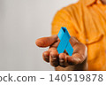 Holding a blue ribbon as a symbol of support for health awareness and advocacy 140519878