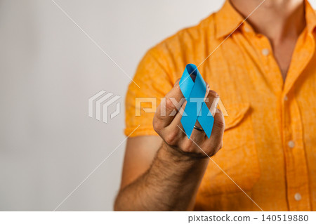 Support for health awareness with a blue ribbon held by a man Support for health awareness with a blue ribbon held by a man 140519880