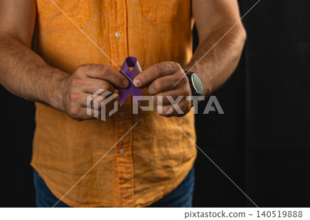 Man holds a purple awareness ribbon showing support for healthcare initiatives 140519888