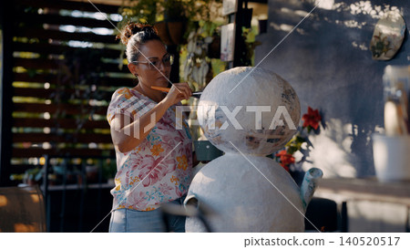 Latina woman crafting paper mache sculpture outdoors 140520517