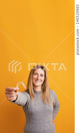 Woman showing invisible aligner for dental care and orthodontics Woman showing invisible aligner for dental care and orthodontics 140520985