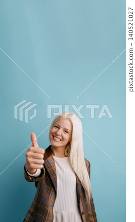 Blonde woman giving thumbs up on blue background 140521027