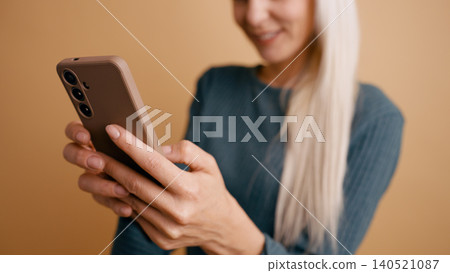 Woman smiling and texting on smartphone Woman smiling and texting on smartphone 140521087