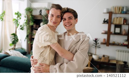 Gay men couple hugging and smiling in living room Gay men couple hugging and smiling in living room 140521112