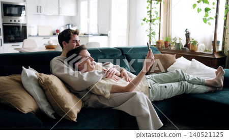 Gay couple relaxing on couch using smartphone 140521125
