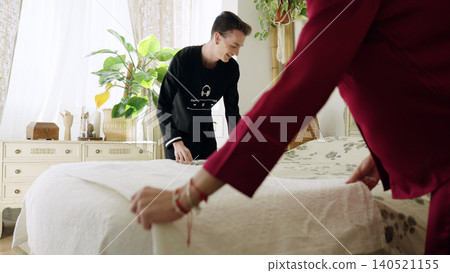 Gay couple making bed together in morning bedroom Gay couple making bed together in morning bedroom 140521155