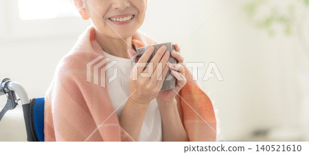一位坐在輪椅上的女士拿著一杯咖啡 140521610