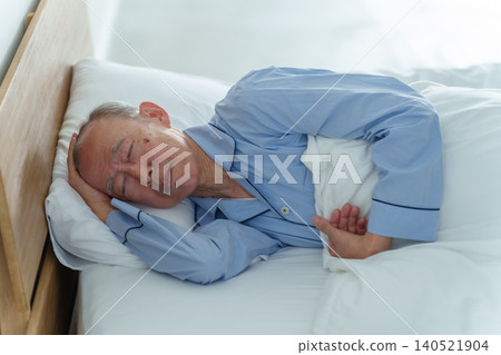一位體弱多病的老人在床上休息。 一位體弱多病的老人在床上休息。 140521904