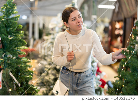 Woman choosing a Christmas tree Woman choosing a Christmas tree 140522170
