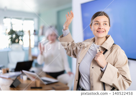 Adult woman leaving office saying goodbye to colleague Adult woman leaving office saying goodbye to colleague 140522458