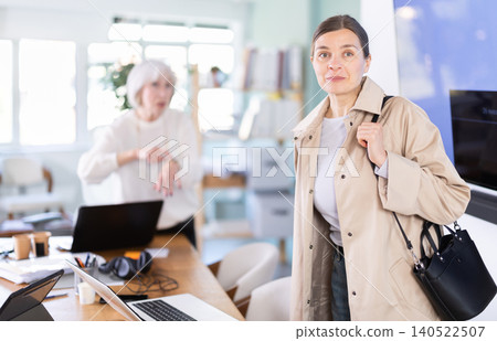 Elderly woman scolding female colleague for being late to office Elderly woman scolding female colleague for being late to office 140522507
