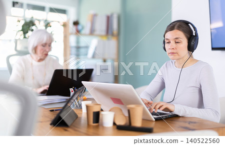 Two businesswomen work on laptops in modern company office 140522560