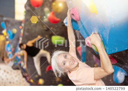Joyful concentrated senior woman busy with her hobby bouldering, climbing on artificial wall in gym, extreme sport, rock-climbing concept Joyful concentrated senior woman busy with her hobby bouldering, climbing on artificial wall in gym, extreme sport, rock-climbing concept 140522799