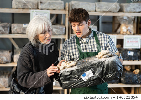 Guy consultant seller, presents mycelium to senior female buyer 140522854