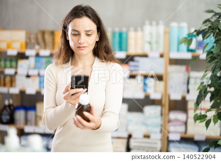 Woman in summer clothes scans code on cough syrup to check expiration date 140522904
