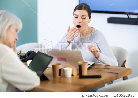 Tired elderly and adult female colleagues fall asleep while working Tired elderly and adult female colleagues fall asleep while working 140522953