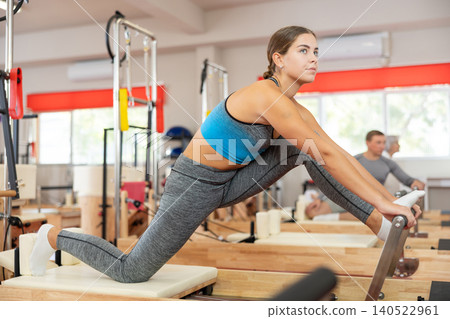 Young woman doing stretching on pilates machine Young woman doing stretching on pilates machine 140522961