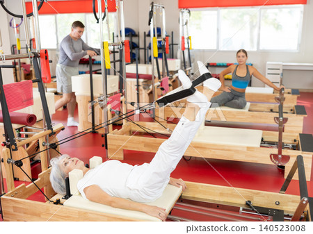 Elderly woman training her legs using straps Elderly woman training her legs using straps 140523008