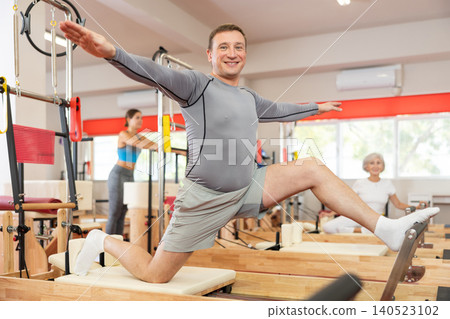 Adult man doing stretching on pilates machine Adult man doing stretching on pilates machine 140523102