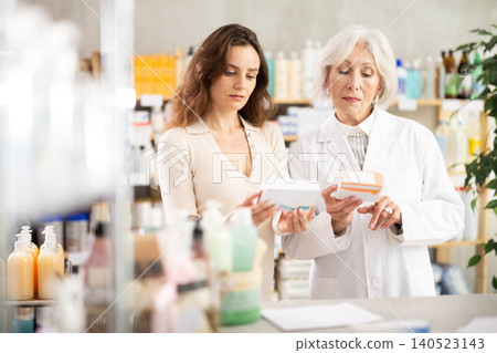 European woman chooses a package of pills in a pharmacy with a pharmacist 140523143