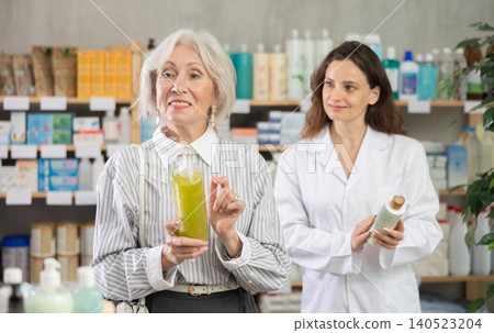 elderly woman chooses a shampoo against the background of a pharmacist elderly woman chooses a shampoo against the background of a pharmacist 140523204