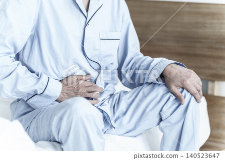 An elderly man clutching his stomach. An elderly man clutching his stomach. 140523647