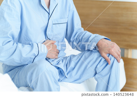 An elderly man clutching his stomach. An elderly man clutching his stomach. 140523648