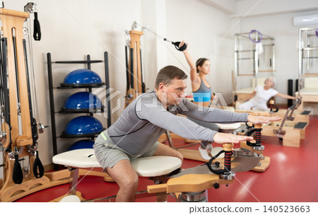 Adult man stretching her arms using pilates machine Adult man stretching her arms using pilates machine 140523663