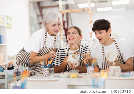 Group of cheerful people painting ceramic dishware in pottery class Group of cheerful people painting ceramic dishware in pottery class 140523710