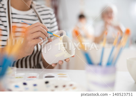 Hands of female artisan painting mug in pottery workshop Hands of female artisan painting mug in pottery workshop 140523751
