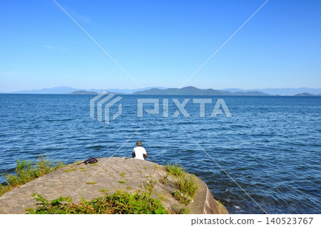 A senior man enjoys fishing alone on the shore of Lake Biwa. A senior man enjoys fishing alone on the shore of Lake Biwa. 140523767