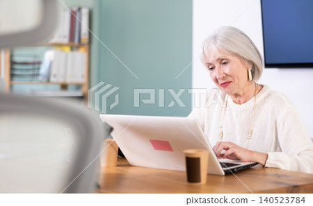 Senior woman working in office, using laptopat workplace. Senior woman working in office, using laptopat workplace. 140523784