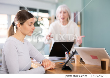 Elderly woman scolding female colleague working on tablet 140523790
