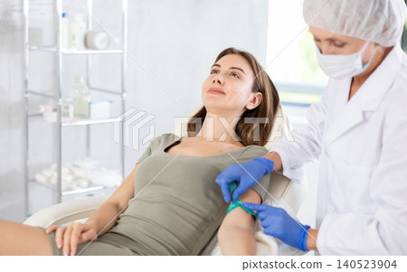 Elderly doctor drawing blood from young patient. 140523904