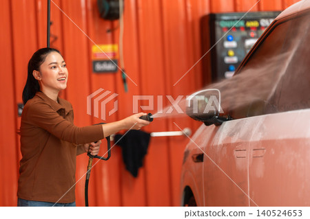 woman washing car with water hose in a self-service car wash station 140524653