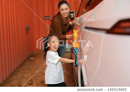 happy child girl with woman washing car with microfiber cloth in a self-service car wash station 140524665