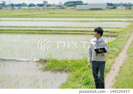 A man in work clothes looking at a rice field. 140526457