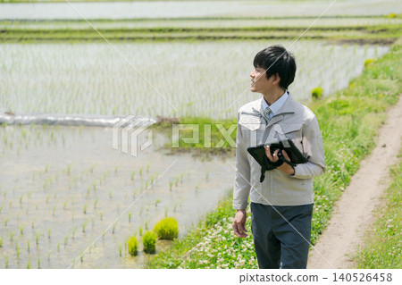A man in work clothes looking at a rice field. 140526458