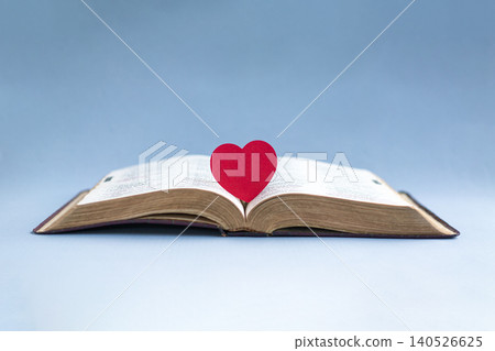 Open bible with a red heart at the center of the pages. 140526625