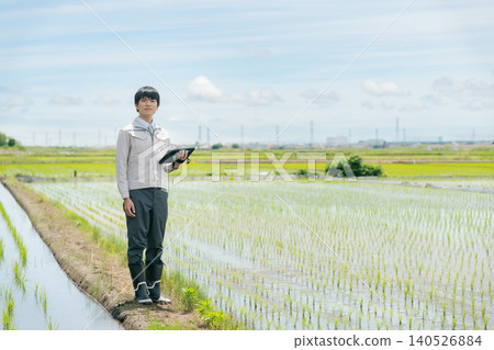 A man in work clothes looking at a rice field. A man in work clothes looking at a rice field. 140526884