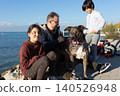Family enjoying time with pet dog by lakeside promenade on sunny day 140526948
