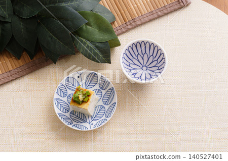A still-life photograph of Japanese food featuring sake and chilled tofu | A calm dining table image with a sacred sakaki branch. A still-life photograph of Japanese food featuring sake and chilled tofu | A calm dining table image with a sacred sakaki branch. 140527401