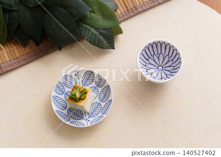 一張描繪日本料理的靜物照片,包括清酒和冰鎮豆腐 | 一張寧靜的餐桌照片,擺放著神聖的榊樹枝。 一張描繪日本料理的靜物照片,包括清酒和冰鎮豆腐 | 一張寧靜的餐桌照片,擺放著神聖的榊樹枝。 140527402